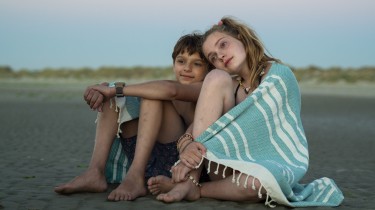 Ein Junge und ein Mädchen sitzen am Strand.